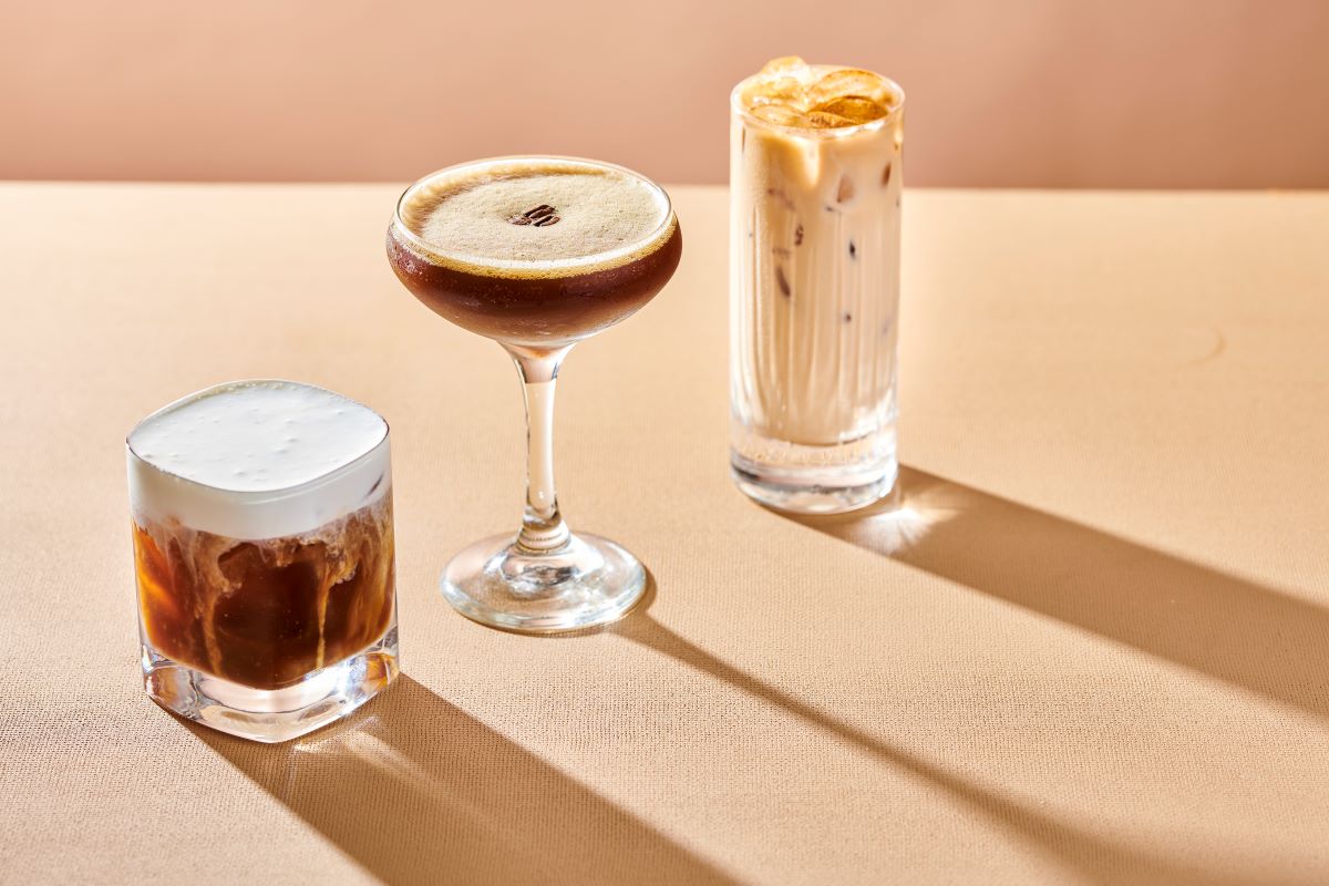 Three different coffee drinks, one that looks like a cold brew in an old fashioned glass, an espresso martini, and an iced coffee in a Collins glass.