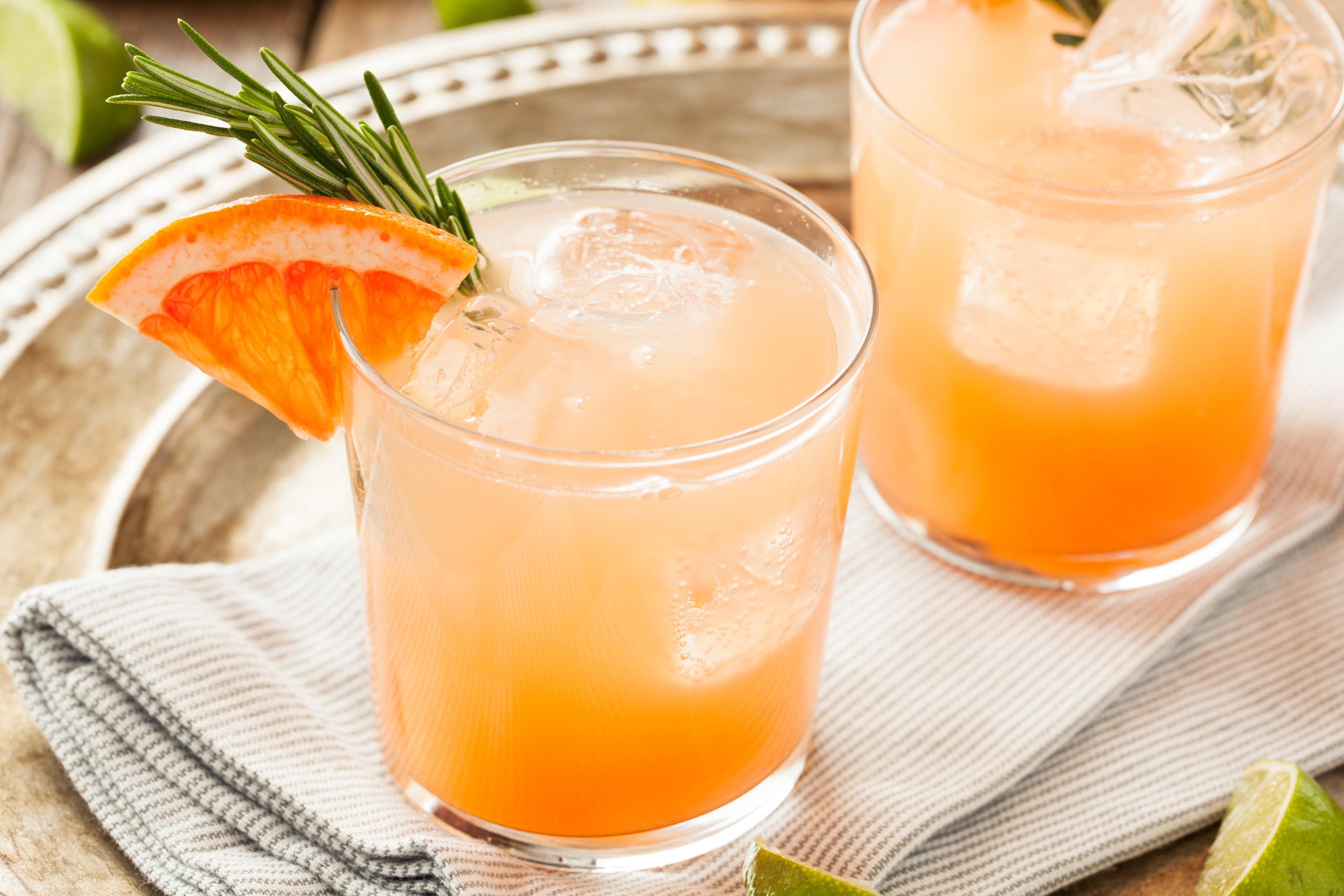 Two grapefruit drinks set upon a silver serving tray.