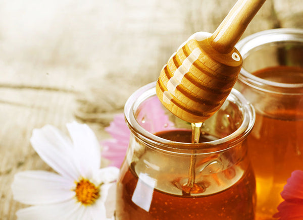 Honey in a jar with a wooden honey dipper.