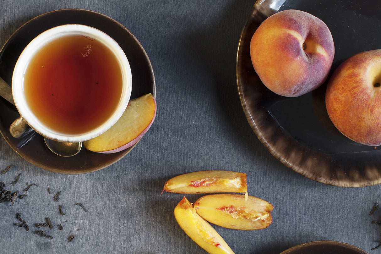 Overhead picture of hot peach tea next to a bowl of peaches.